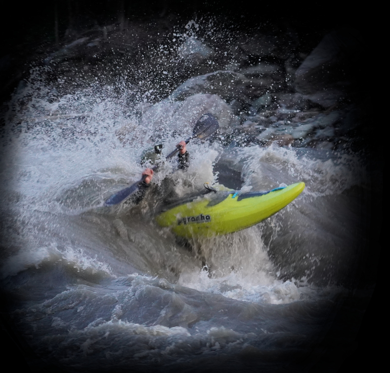 A kayaker Kool-Aid-manning a breaking wave on the Nenanan River. The kayaker's face and body are obscured by the exploding water, and only their yellow kayak, black paddle, and gray helmet are visible.